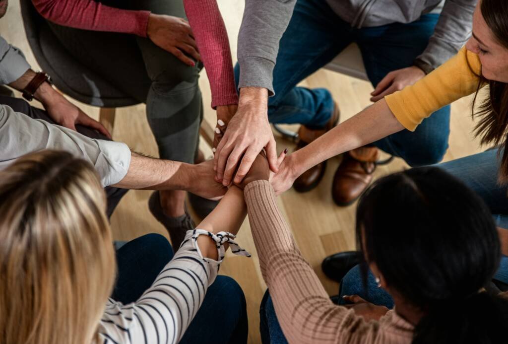 Diverse group of people sitting in circle in group therapy session.